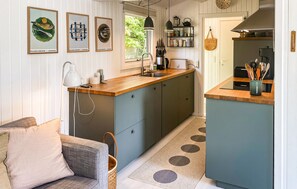 A compact kitchen with a wooden countertop, a built-in sink, and a dining area with a sofa and a coffee table. - Stunning home in Sjællands Odde with WiFi (Sjællands Odde)
