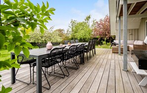 An outdoor patio with a wooden deck, a table with chairs, and a wicker sofa. - Amazing home in Assens with WiFi (Assens)