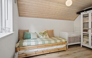 A bedroom with a wooden bed, a crib, a white wardrobe, and a window with a white headboard. - Amazing home in Assens with WiFi (Assens)
