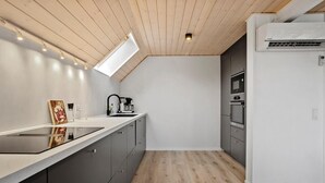 Una cocina moderna con techo de madera, estufa integrada y refrigerador.