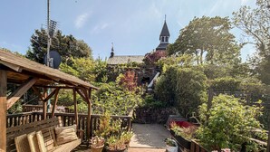 A garden with a wooden pergola, potted plants, and a stone wall. - 1 bedroom gorgeous apartment in Gudhjem (Gudhjem)