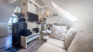 A modern loft-style living space with a television, speakers, a sofa, and a small table. - 1 bedroom gorgeous apartment in Gudhjem (Gudhjem)
