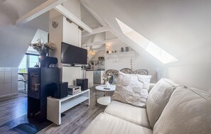 Ein moderner Loft-Wohnraum mit Fernseher, Lautsprechern, einer Couch und einem kleinen Tisch.