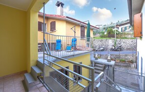 A balcony with metal railings, a yellow wall, and a view of a street with parked scooters. - 2 bedroom nice home in Monte Isola (Monte Isola)