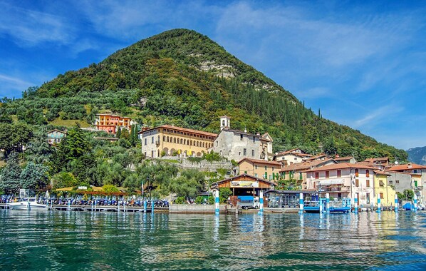 A lakeside village with traditional buildings, a church, and a dock with boats. - 2 bedroom nice home in Monte Isola (Monte Isola)