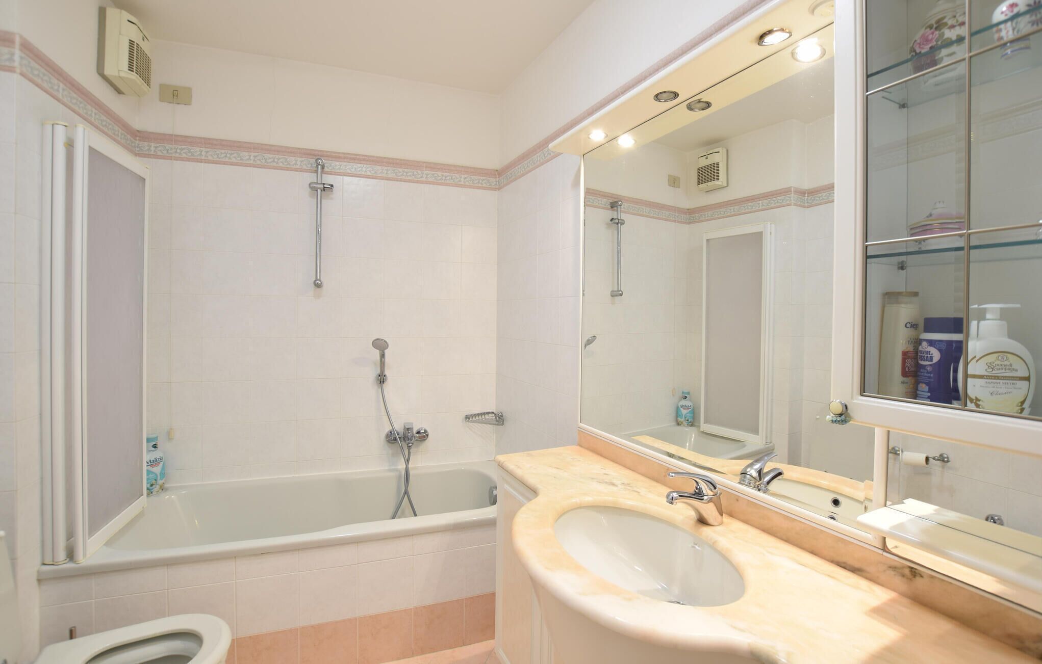 A bathroom with a bathtub, a sink, a shower, and a mirror.