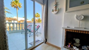 Habitació amb porta corredissa de vidre que dona a un balcó amb cadires i palmeres.