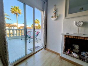 A room with a sliding glass door leading to a balcony with chairs and palm trees. -  APARTMENT NEXT TO THE BEACH A/C  ROOF TERRACE WIFI UK TV SPANISH (Torrevieja)