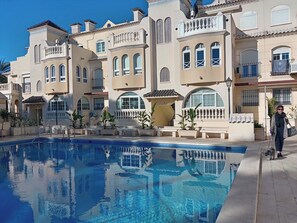 A pool area with a clear blue pool, surrounded by buildings with balconies and arched windows. -  APARTMENT NEXT TO THE BEACH A/C  ROOF TERRACE WIFI UK TV SPANISH (Torrevieja)