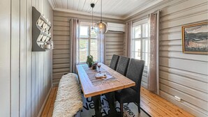 Un coin repas avec une table en bois, des chaises, un tapis moelleux et un luminaire suspendu.