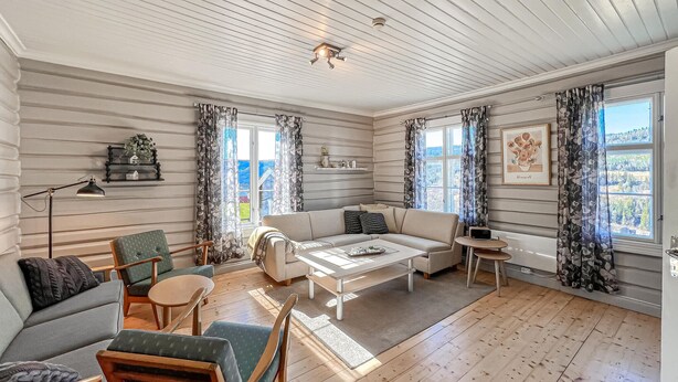 Un salon chaleureux avec un canapé, des fauteuils, une table basse et une cheminée.