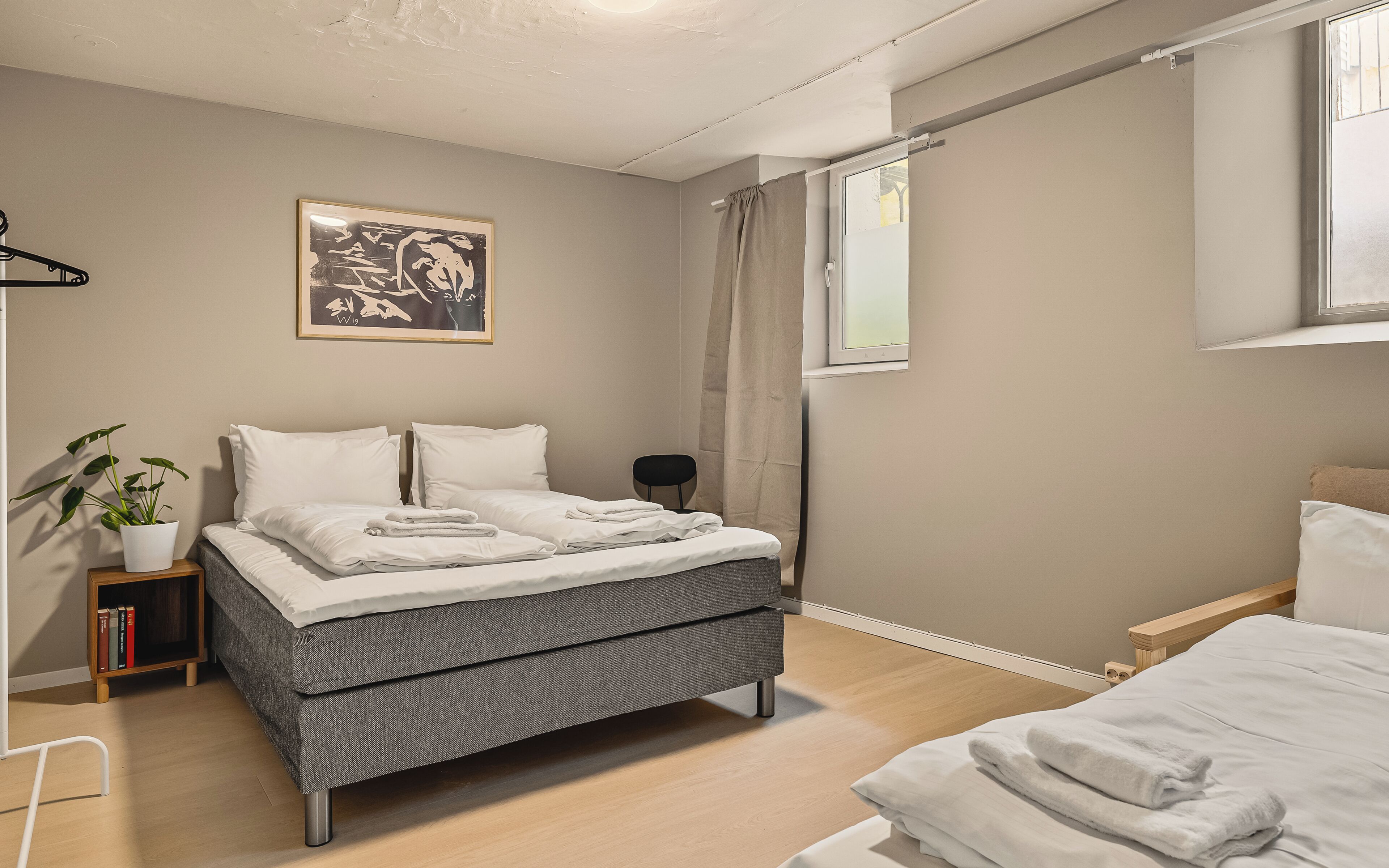 A modern bedroom with a bed, bedside table, and a potted plant.