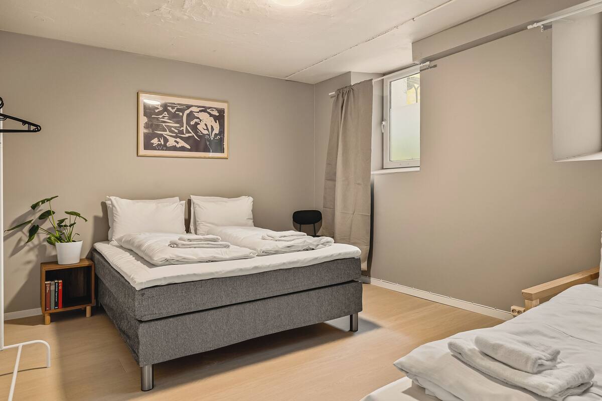 Un dormitorio moderno con cama, mesita de noche y una planta en maceta.