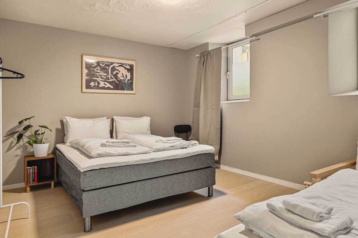 A modern bedroom with a bed, bedside table, and a potted plant.