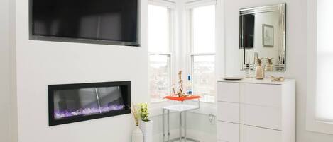Un baño moderno con un espejo grande, un tocador blanco y una chimenea.