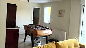 A living room with a yellow sofa, a foosball table, and a dark wooden cabinet. - Grande Maison Familiale Chez Paulette ★ Games, Petanque & Nature (Gouzon)