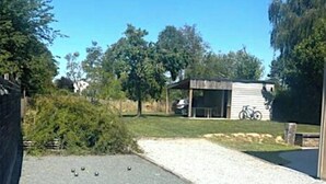 A paved driveway leading to a building with a covered area and a bicycle parked nearby. - Grande Maison Familiale Chez Paulette ★ Games, Petanque & Nature (Gouzon)