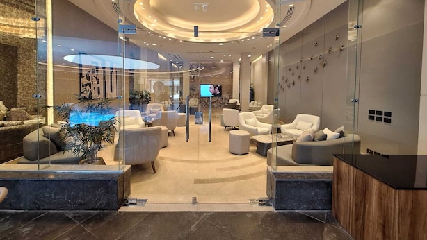 Een moderne lobby met zitgedeeltes, een receptiebalie en een televisiescherm.