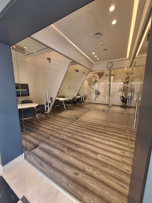 Ein modernes Büro mit Glastrennwänden, Holzboden und einer Uhr an der Wand.