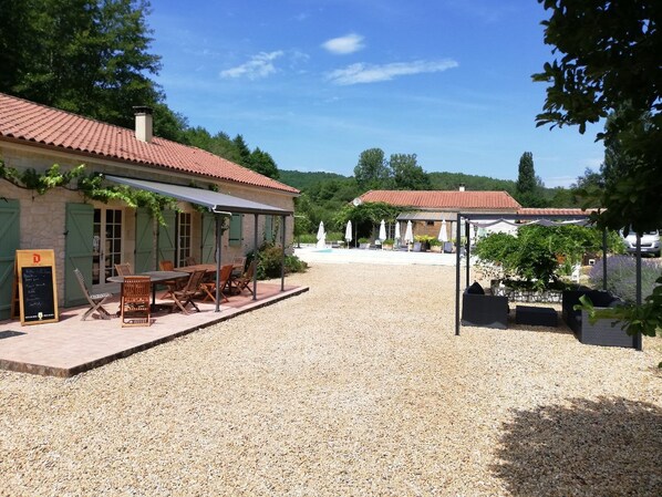 A building with a tiled roof, outdoor seating area, and a gravel courtyard.