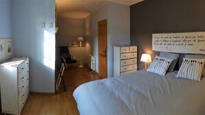 Una camera da letto con un letto, una cassettiera e una scrivania con una sedia.