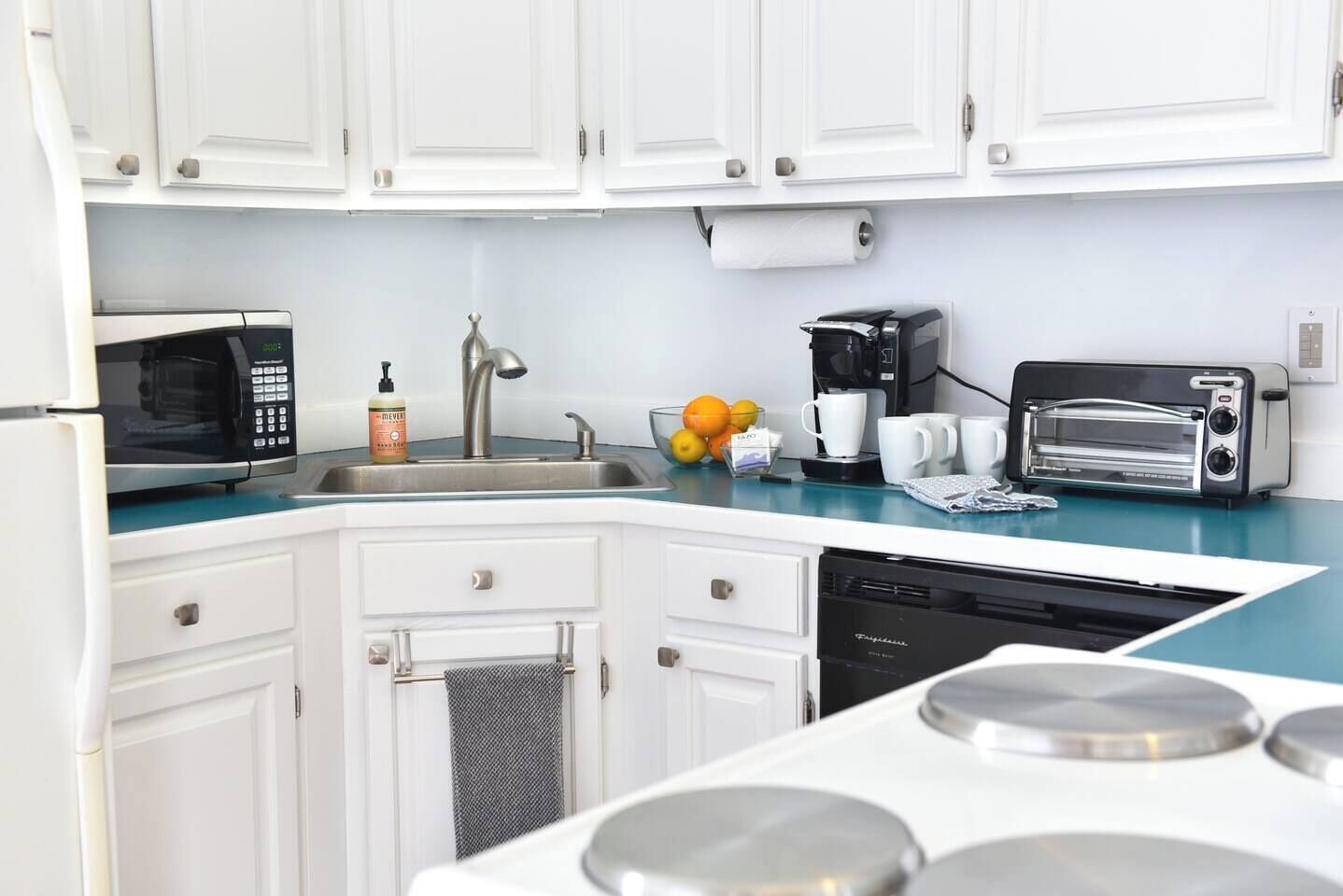 A modern kitchen with white cabinets, a microwave, a coffee maker, a toaster, and a dishwasher.