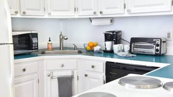 A modern kitchen with white cabinets, a microwave, a coffee maker, a toaster, and a dishwasher.