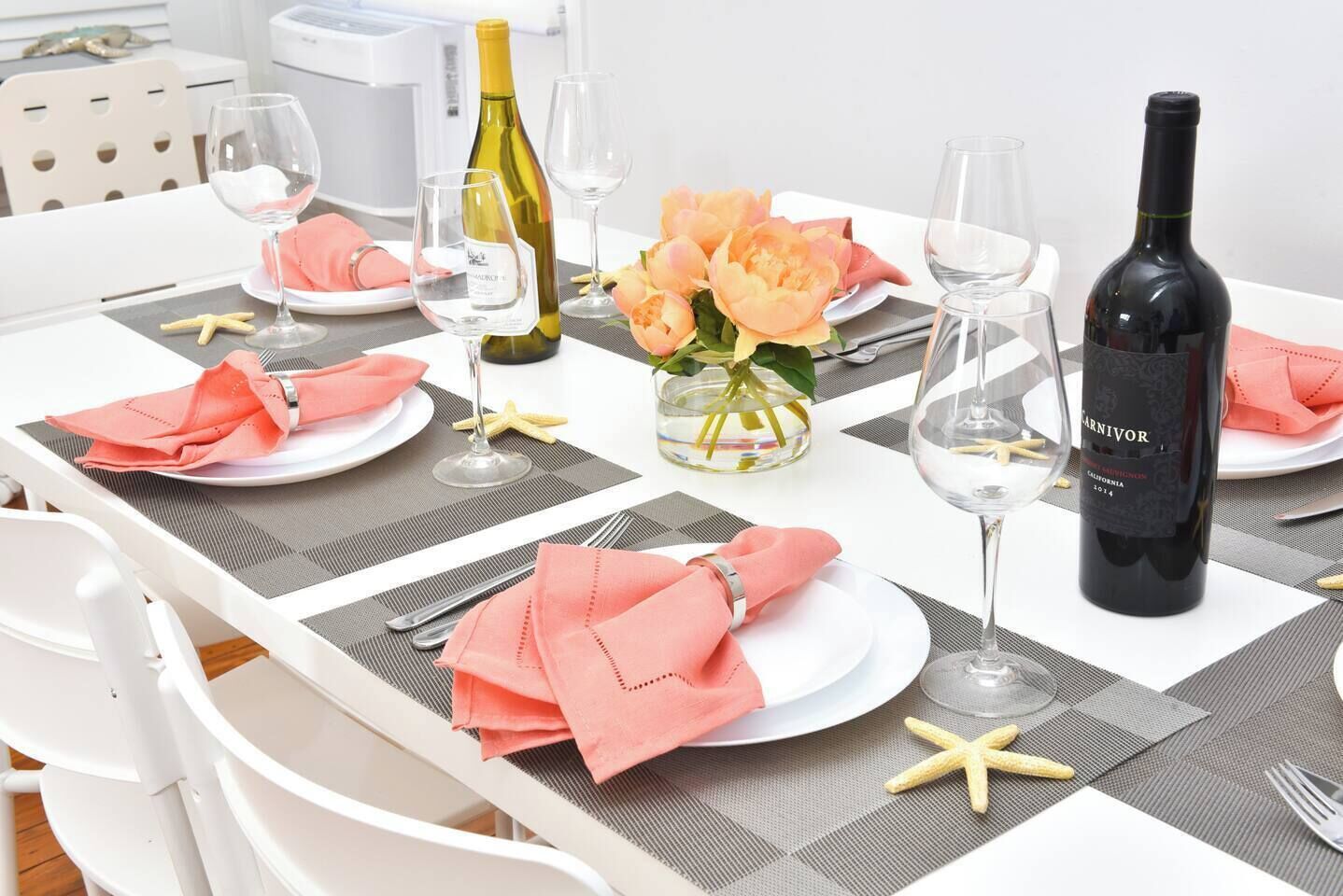 A dining table set with plates, cutlery, wine glasses, and a bottle of wine.
