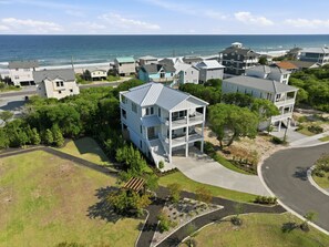 A coastal residential area with houses, a beach, and a clear sky.