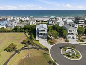 A coastal residential area with houses, a curved road, and a view of the ocean.