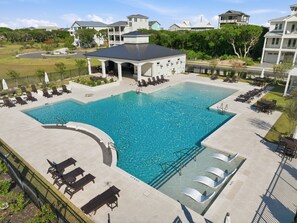Une grande piscine rectangulaire dotée de nombreuses chaises longues et d’un espace salon abrité.