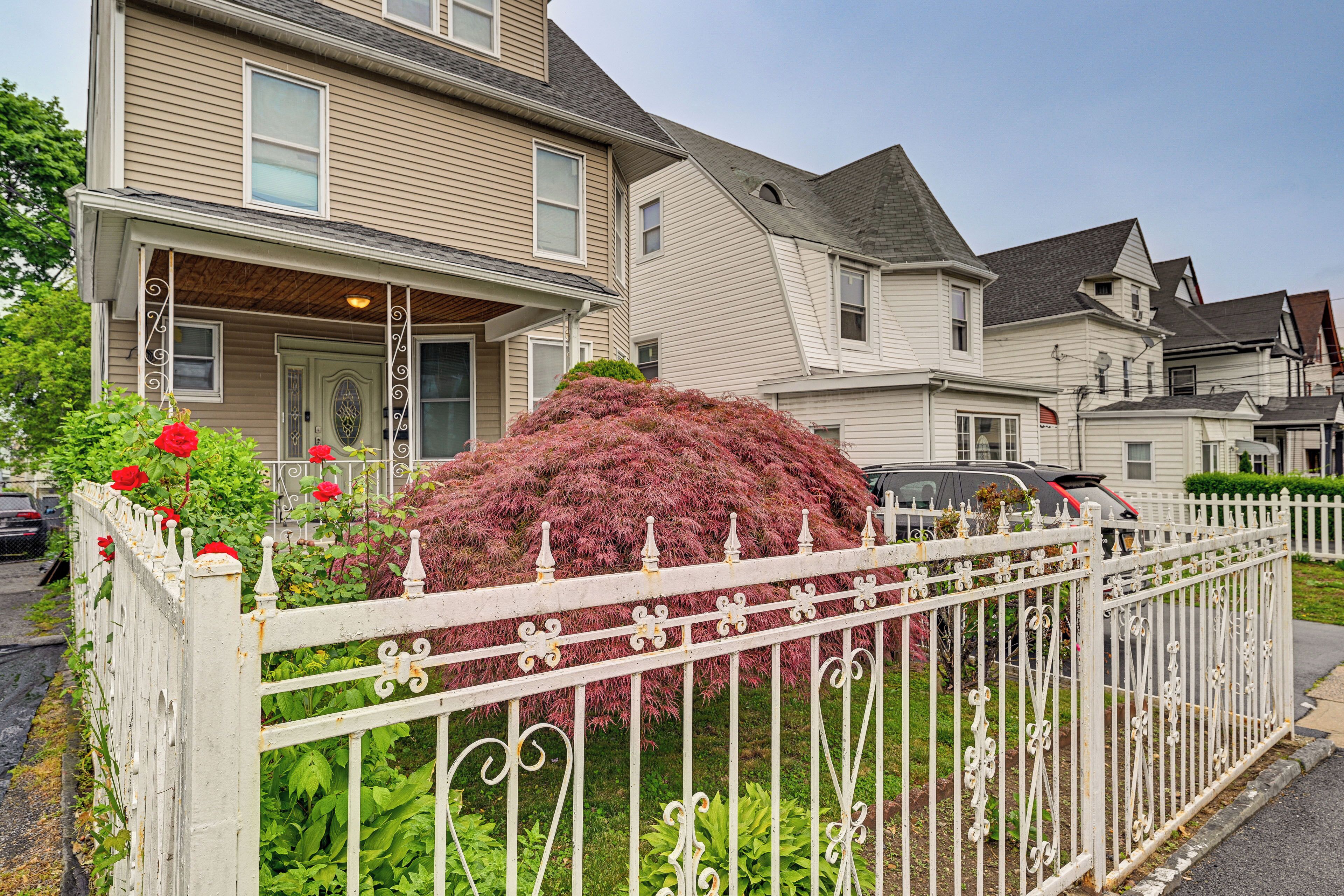 A residential area with houses, a white picket fence, and a large bush.