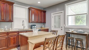 A kitchen with wooden cabinets, a granite countertop, and a dining area with chairs and stools.