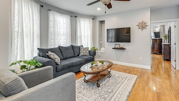 A living room with a grey sofa, a coffee table, and a ceiling fan.