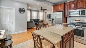 A modern kitchen with wooden cabinets, stainless steel appliances, and a dining area with a granite countertop.