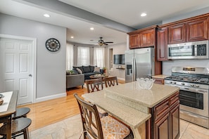 A modern kitchen with wooden cabinets, stainless steel appliances, and a dining area with a granite countertop. - Walk to the NYC Train! Mt Vernon Escape w/ Patio (Mount Vernon)