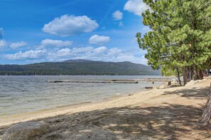 A lakeside view with a dock, trees, and a distant mountain range. - Beach & Dock Access! Waterfront Payette Lake Home (McCall)
