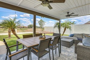 Eine Außenpatio mit Tisch und Stühlen, einer Couch und einem Deckenventilator.
