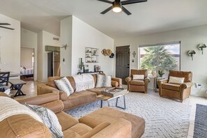 Ein geräumiges Wohnzimmer mit einer Eckcouch, einem Couchtisch und einem Deckenventilator.