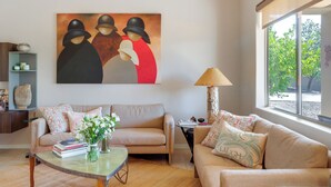 A living room with a sofa, a coffee table, a painting, and a lamp. - Golf, Hike & Unwind: Oro Valley Townhome w/ Patio! (Oro Valley)