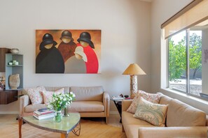 A living room with a sofa, a coffee table, a painting, and a lamp. - Golf, Hike & Unwind: Oro Valley Townhome w/ Patio! (Oro Valley)