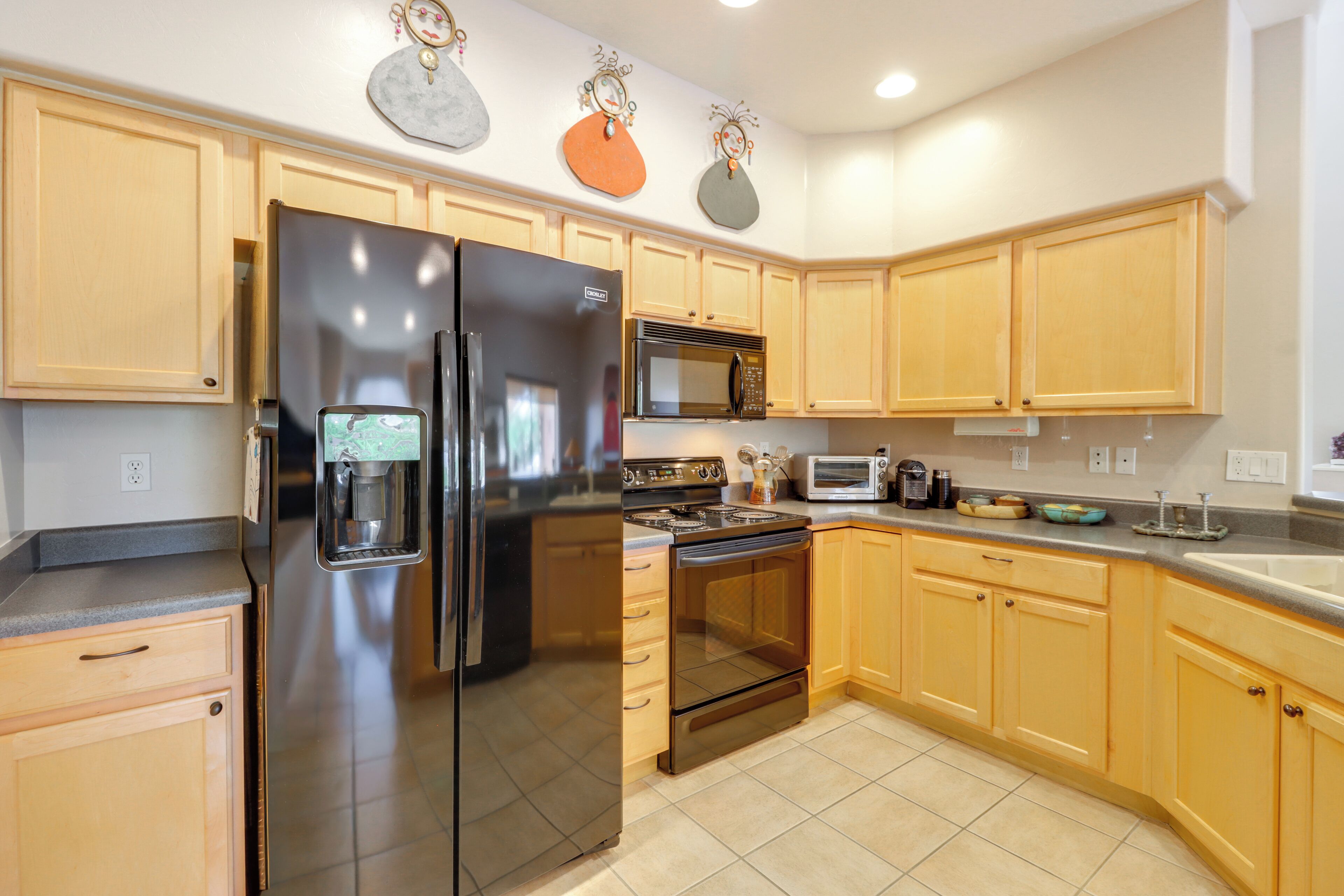 A kitchen with wooden cabinets, a stainless steel refrigerator, a microwave, and an oven.