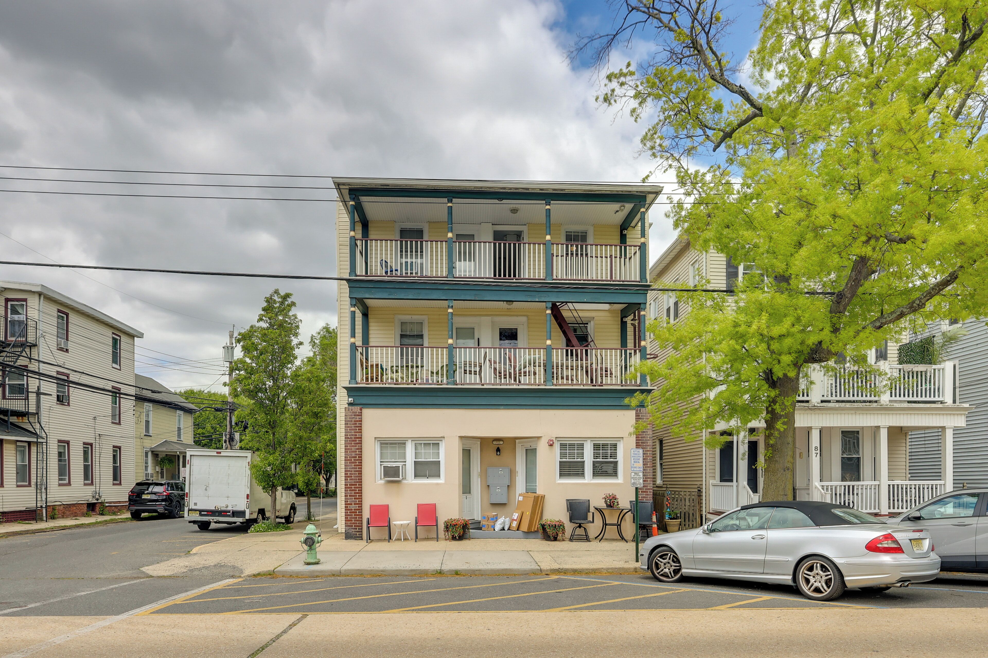 A two-story building with a balcony, a fire hydrant, and a parked car.