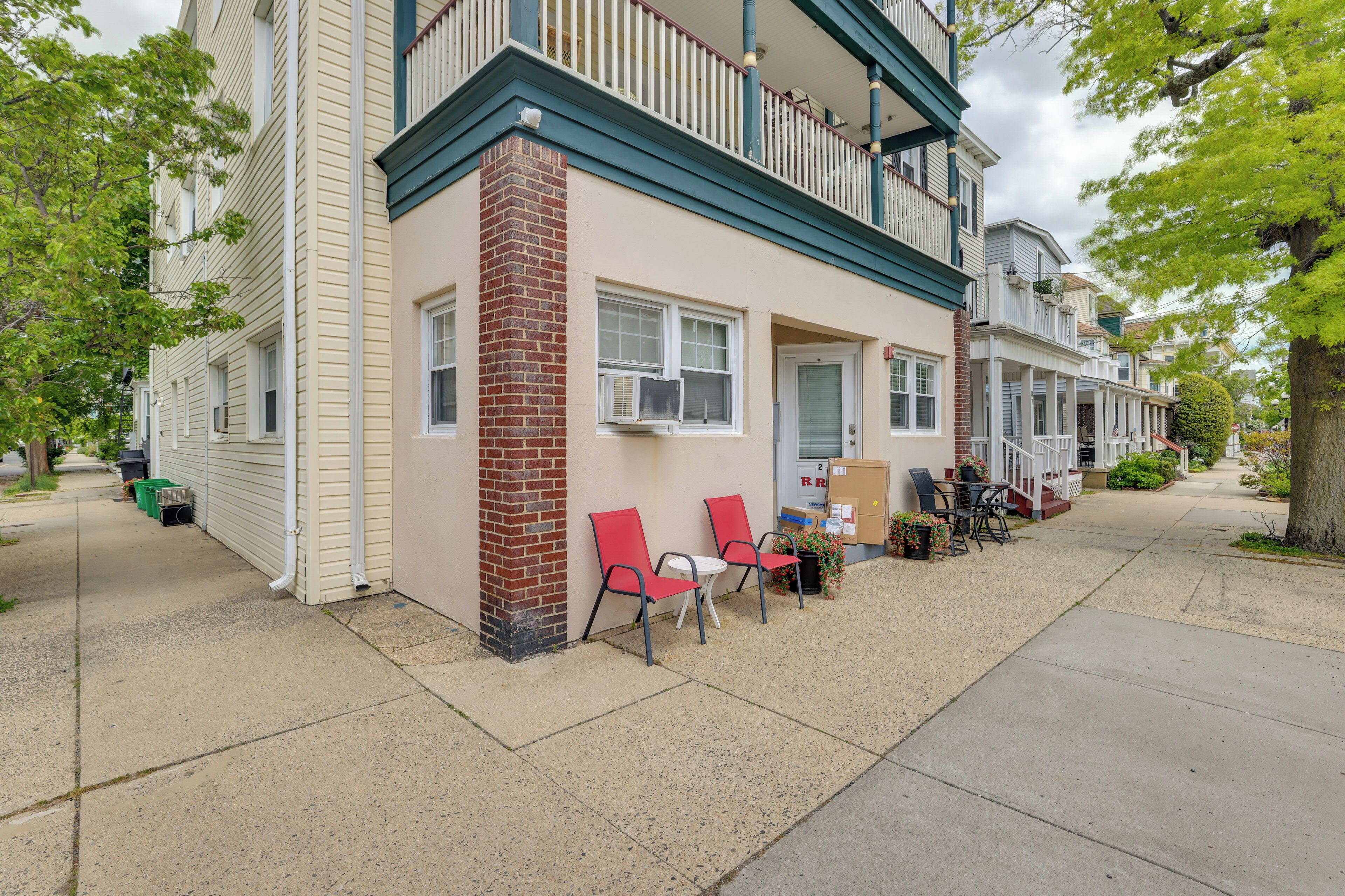 A row of townhouses with a front porch, a brick column, and red chairs outside.