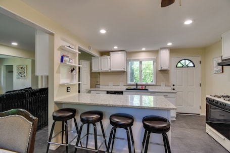 A kitchen with a central island, bar stools, a stove, and a window with a view.. Greece Family Getaway: 2 Mi to Ontario Beach!