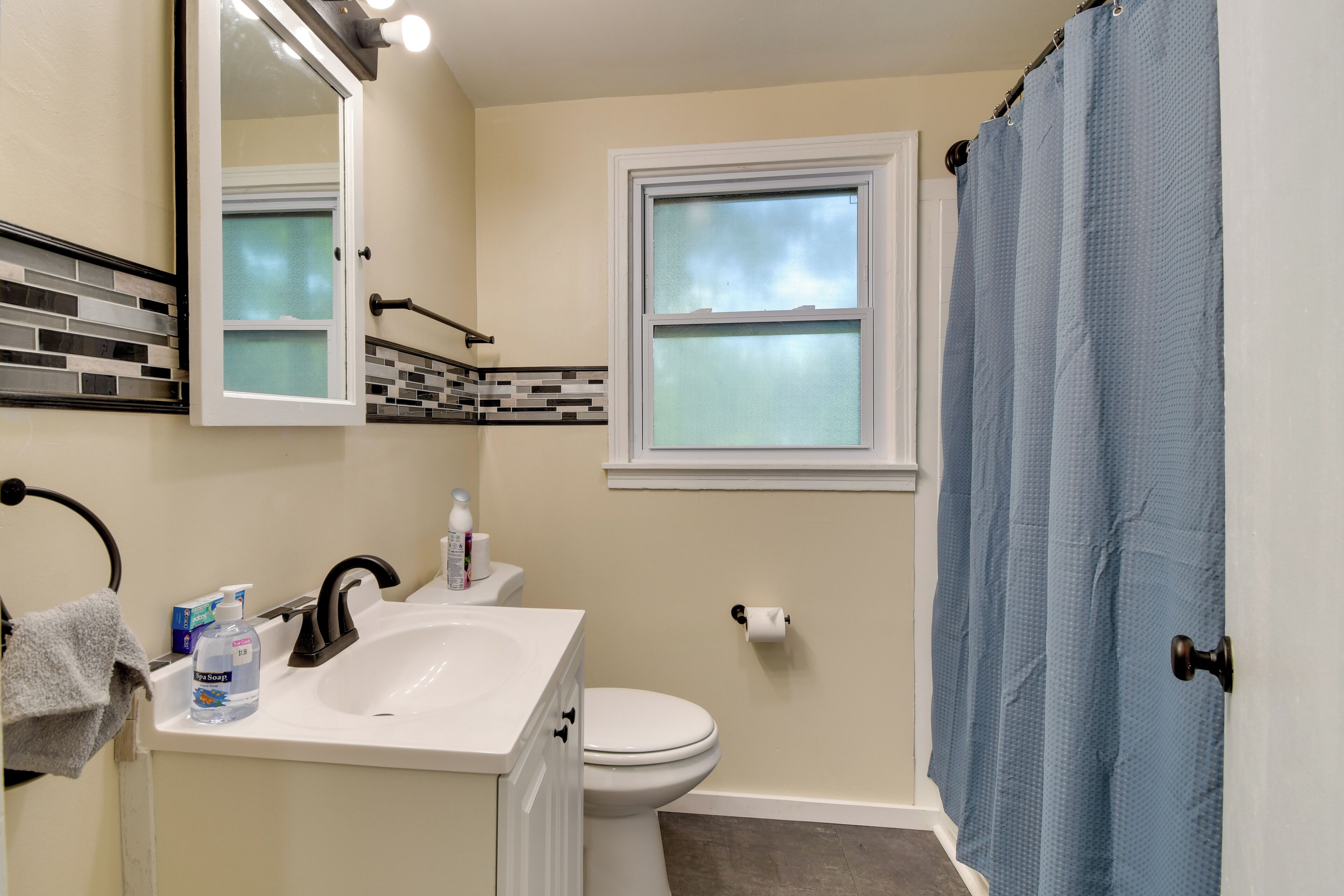 A bathroom with a sink, toilet, and window.