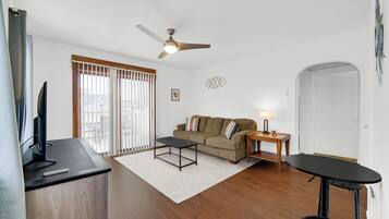 A living room with a sofa, a coffee table, a TV, and a ceiling fan.