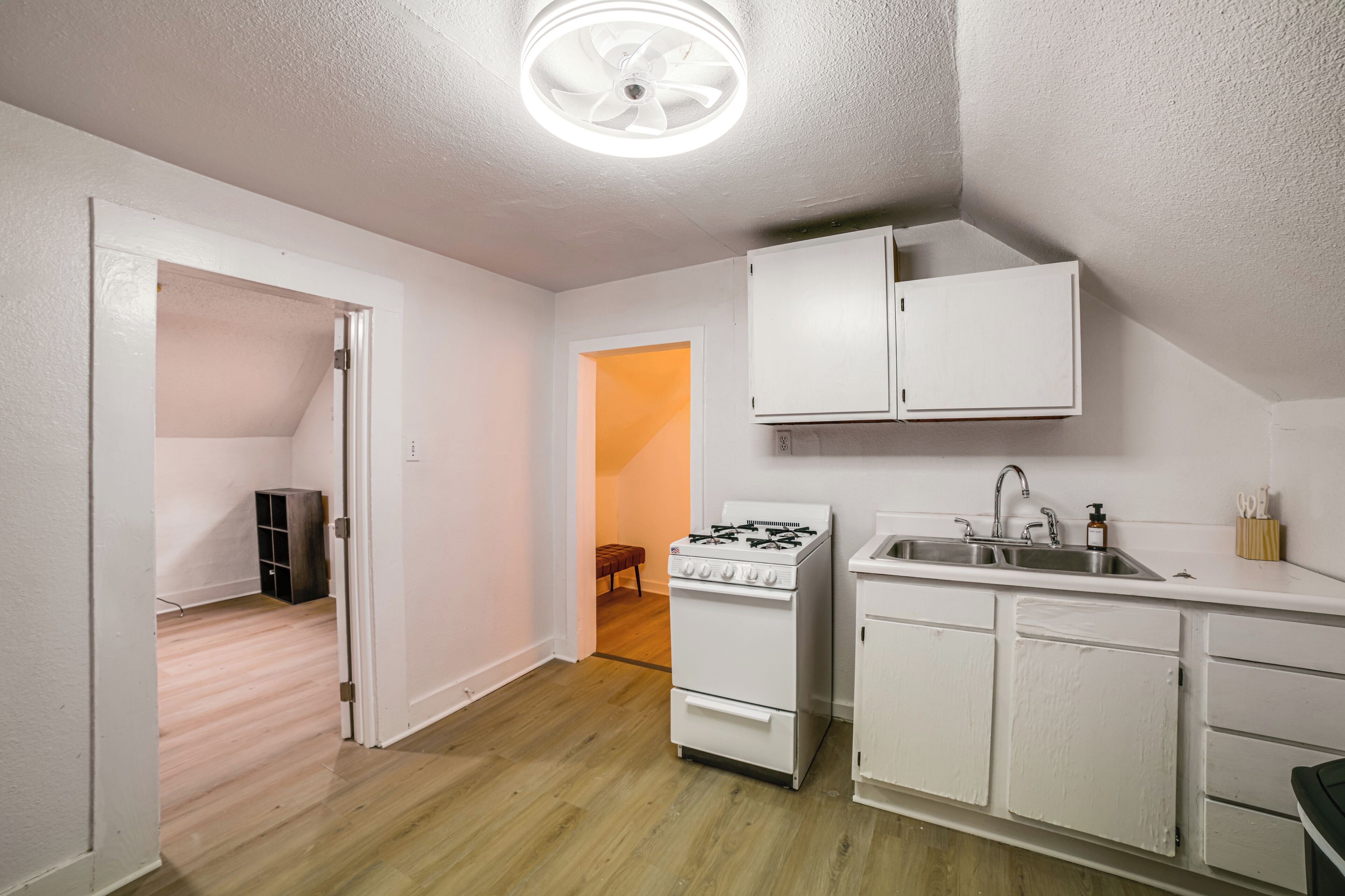 A kitchen with white cabinets, a gas stove, and a sink.