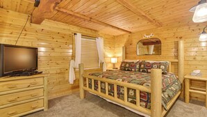 A wooden cabin-style bedroom with a bed, dresser, TV, and a mirror. - Hike, Fish & Ride Atvs! Forest-view Unit in Kamas (Evanston)
