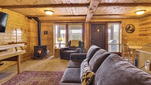 A cozy cabin interior with a fireplace, leather sofa, dining table, and wooden walls. - Hike, Fish & Ride Atvs! Forest-view Unit in Kamas (Evanston)
